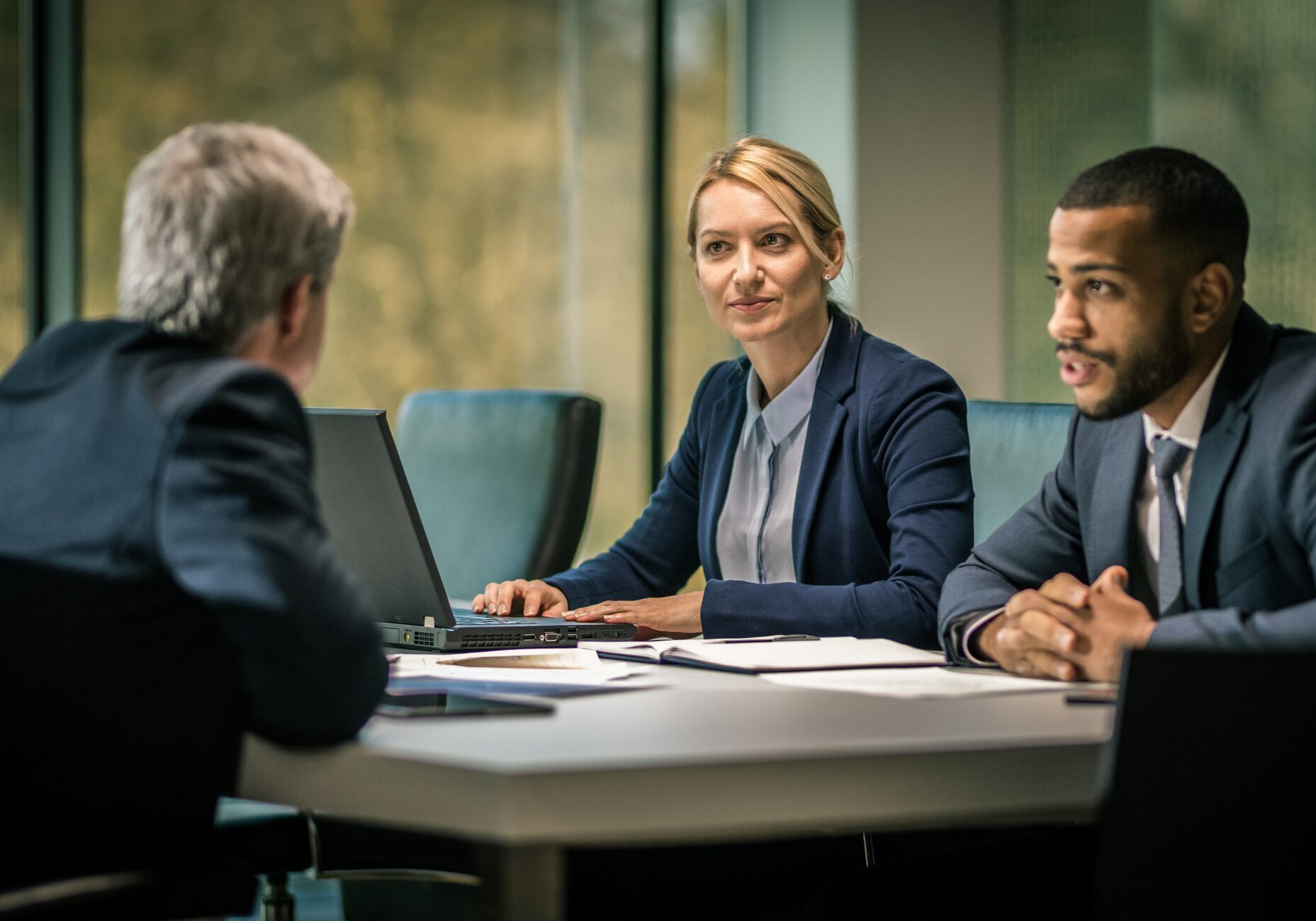 Three people sitting at a table and talking during a business meeting.